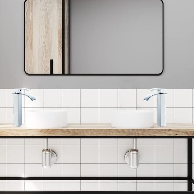 Bathroom vanity with two silver faucets, wooden countertop, and tiled wall.