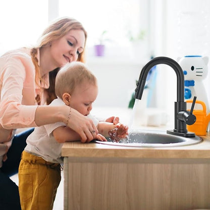 Woman and child washing hands in a kitchen sink with a black faucet.