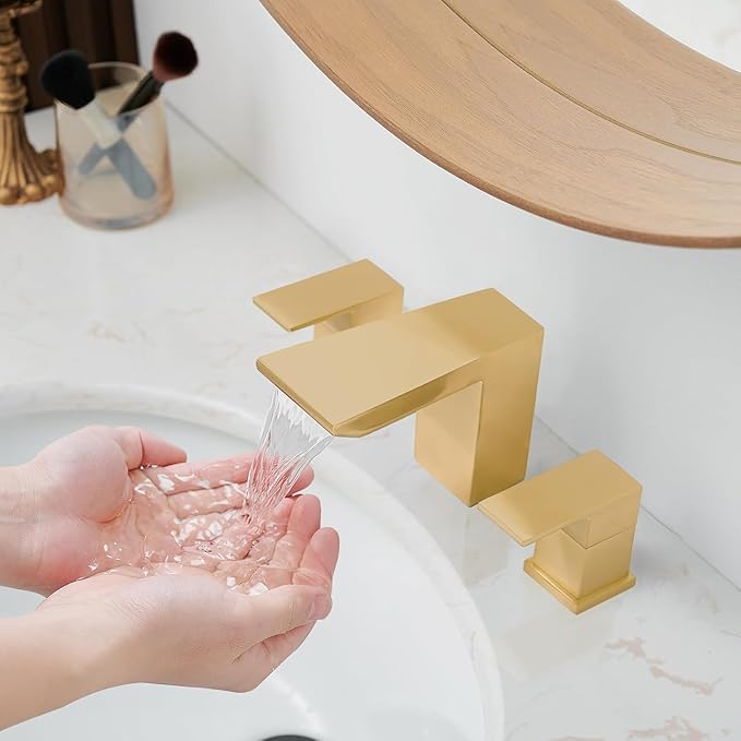 Gold faucet with water flowing into hands over a white sink.