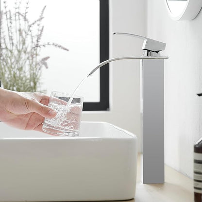 Person filling a glass with water from a modern faucet in a bathroom.