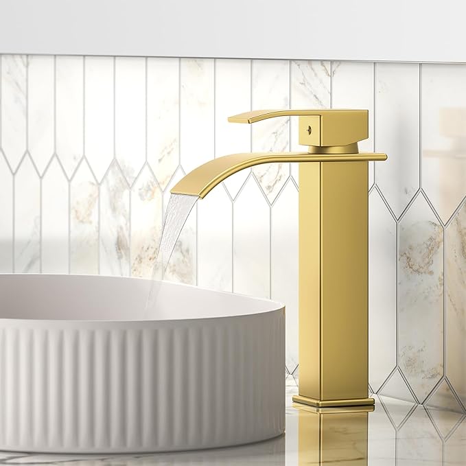 Gold faucet over a white bathtub with a tiled wall background