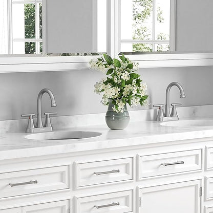 Bathroom vanity with double sink, faucet, and a vase of flowers.